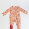Baby onesie with floral pattern and red polka dot feet on a white background