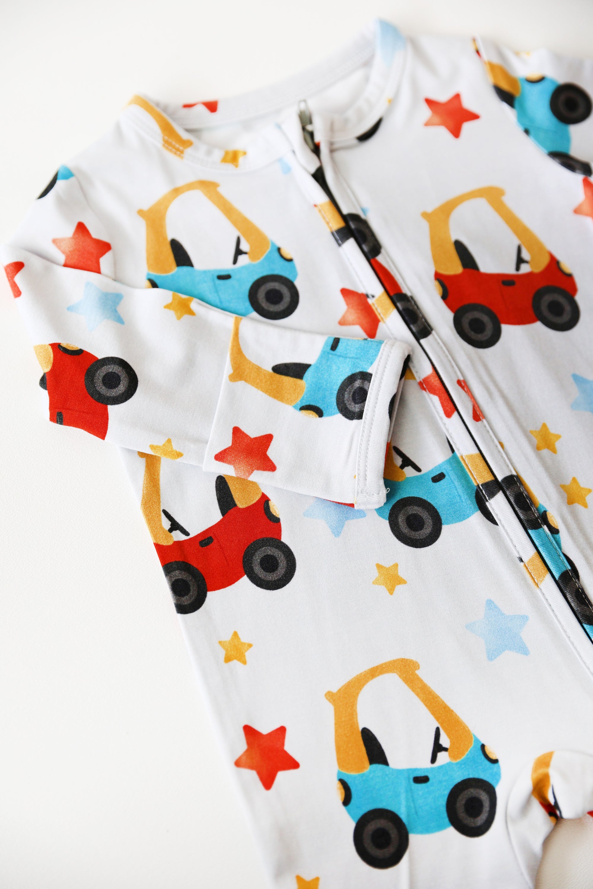 Children's onesie with colorful car and star pattern on a white background