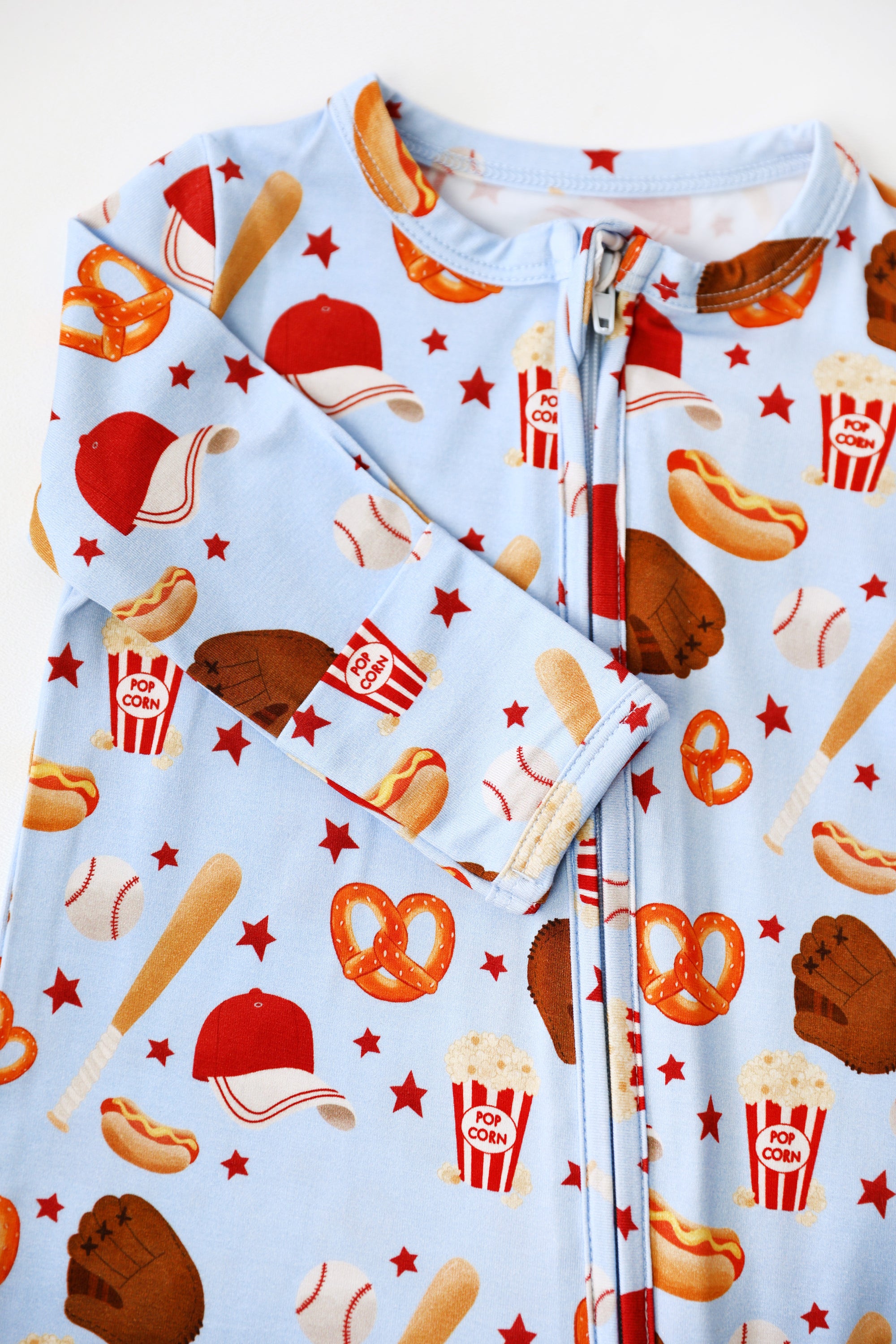 Children's onesie with sports-themed print on a light blue background